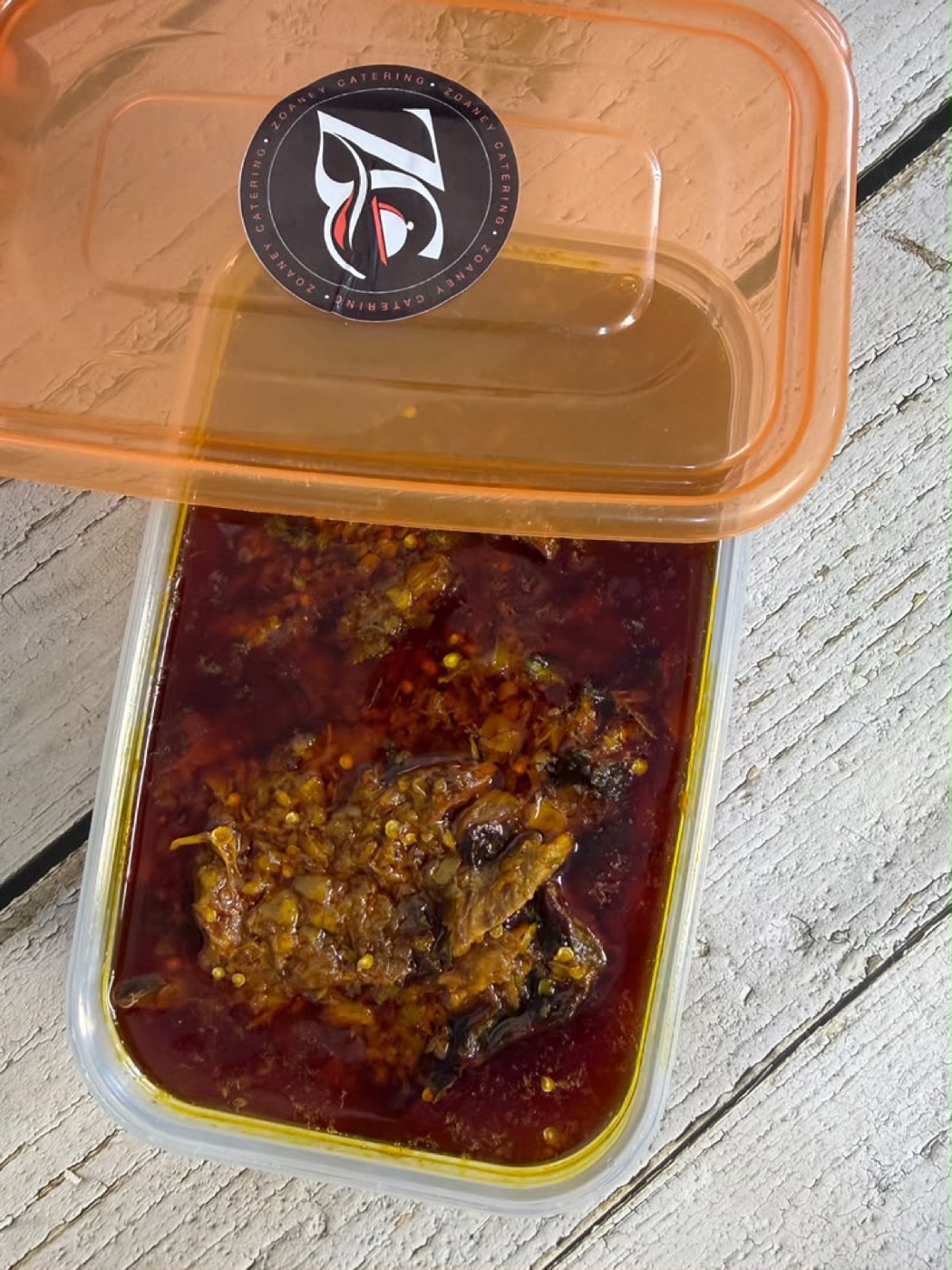 Deep red hangover sauce in a Zoaney container