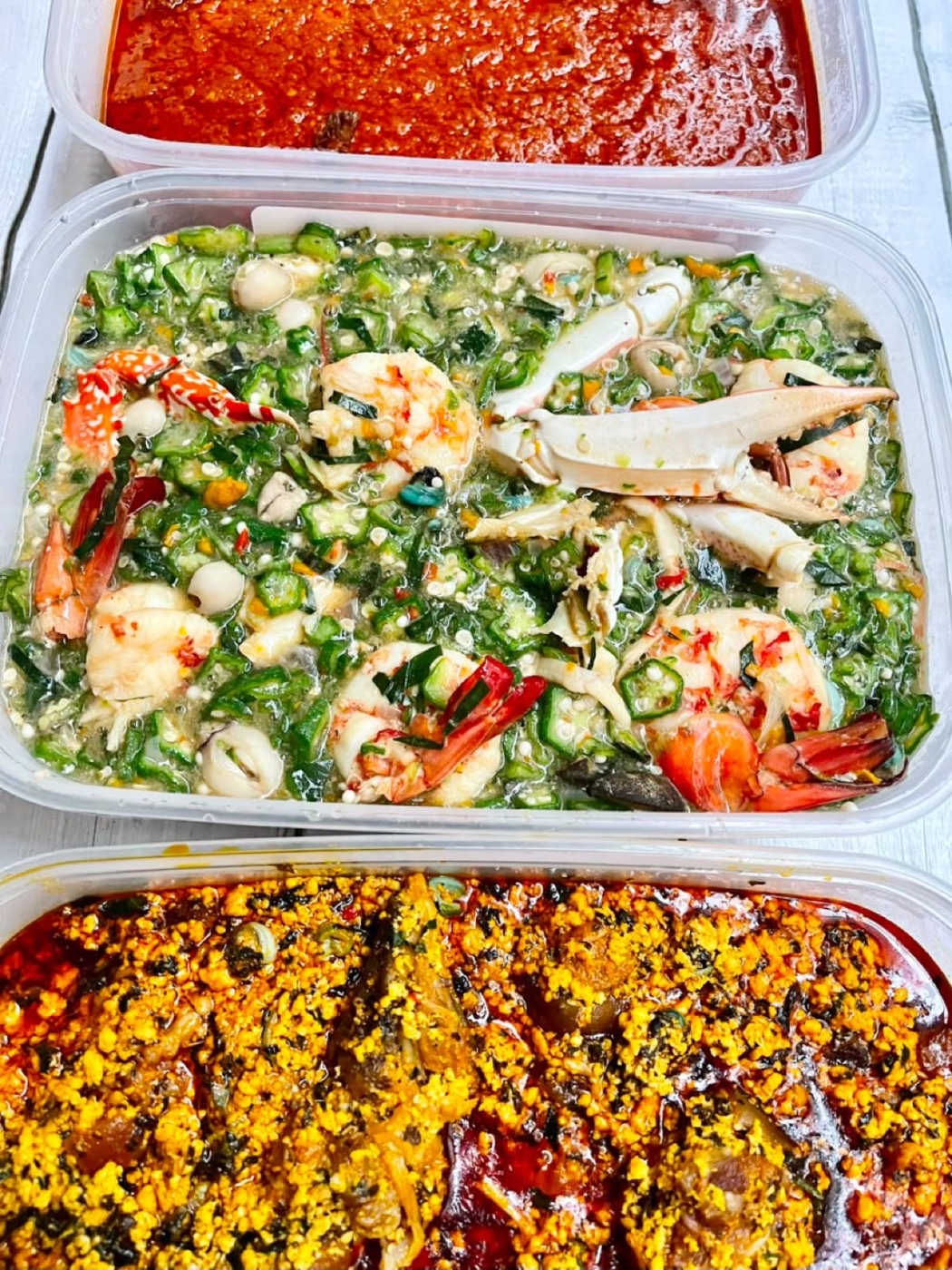 Trays of seafood salad, jollof rice and stew prepared for a large order